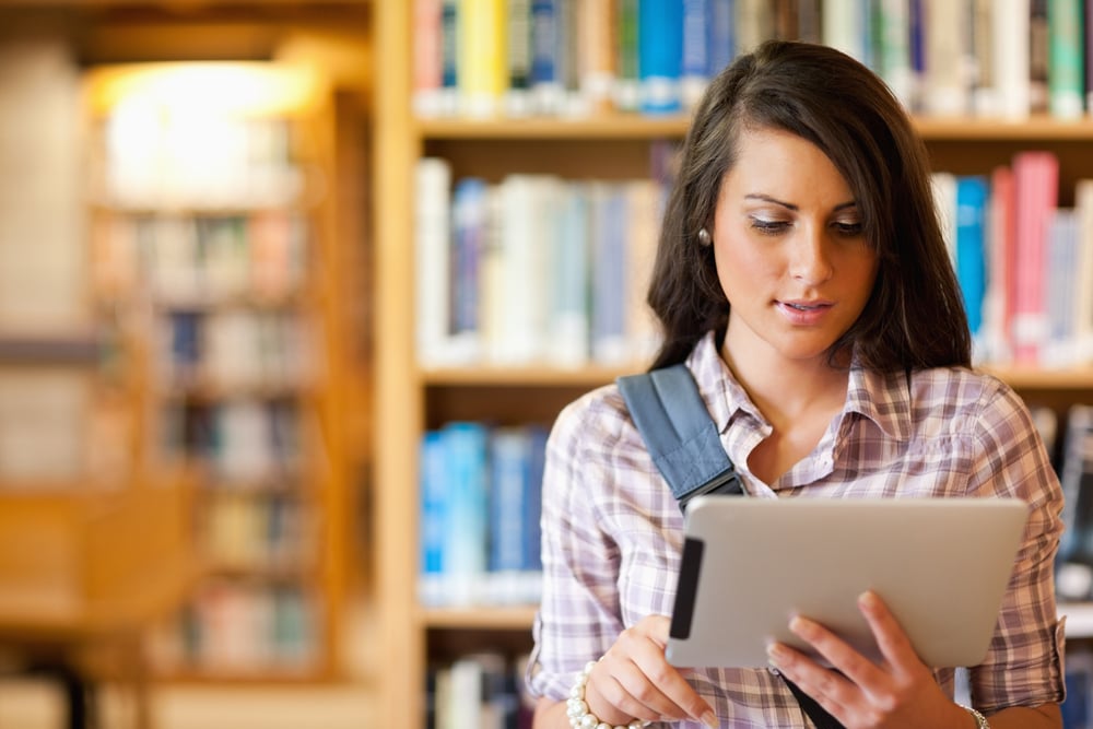 Young focused student using a tablet computer in a library