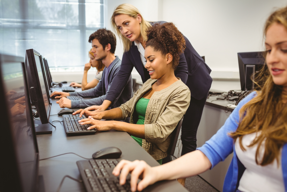 Attractive teacher helping her student in computer class at the university