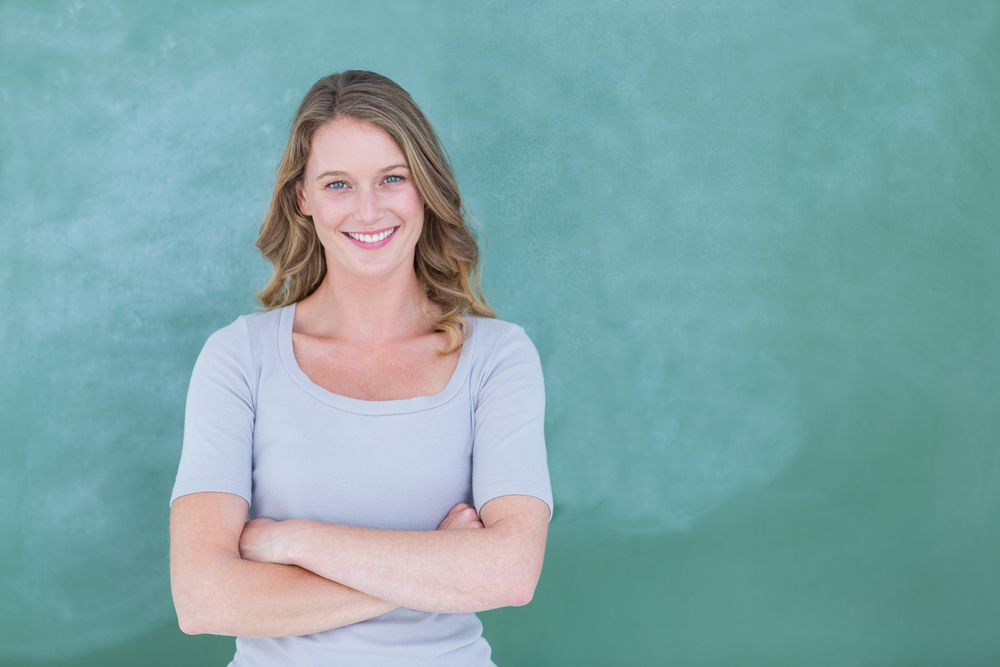 Smiling teacher standing in front of blackboard in classroom