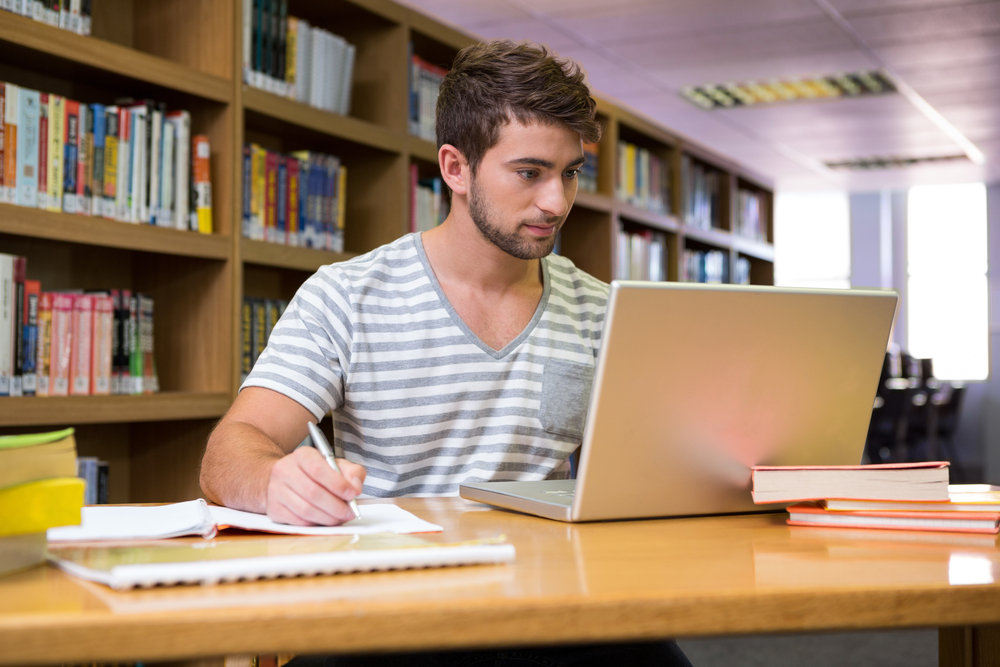 Student studying in the library with laptop at the university